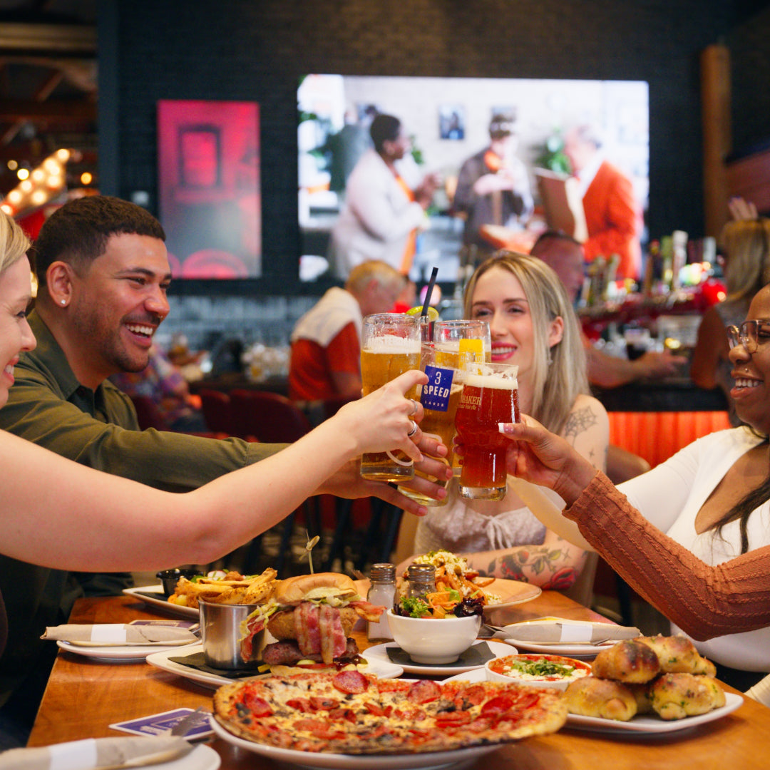 Five people toast with beer from our brewery, enjoying the food and cozy atmosphere in the restaurant. 